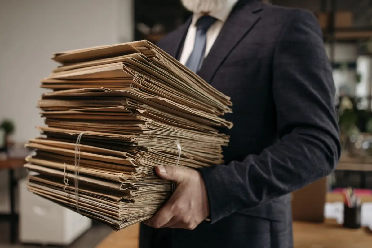 Man in a suit holding a stack of old file folders